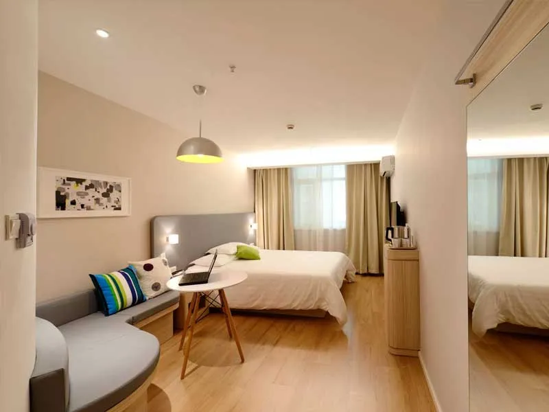 A modern bedroom suite with a reading nook, desk and pendant light